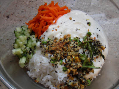 In a big bowl add steamed rice, grated carrots, chopped cucumber, salt and the mustard seeds tempering