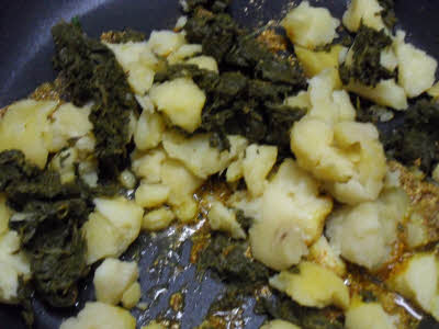 Add broken potatoes and drained bathua leaves