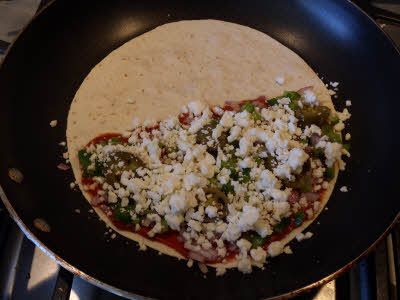 Spread vegetables and cheese on tortilla